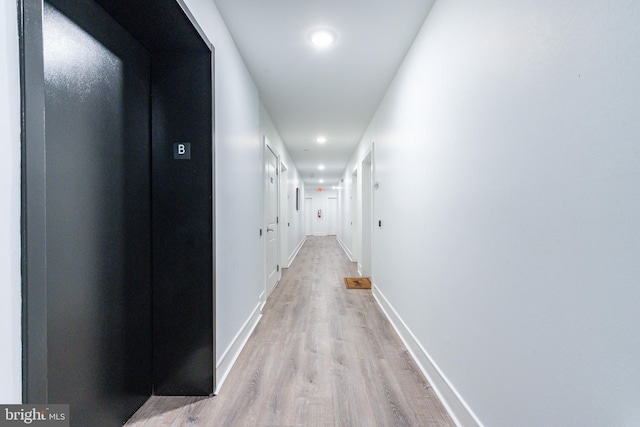 hall with light wood-type flooring and elevator