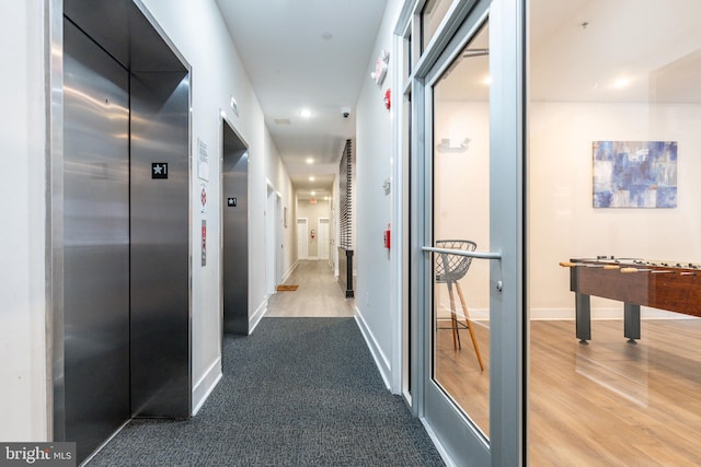 corridor with hardwood / wood-style flooring and elevator