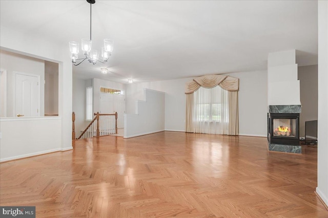 unfurnished living room with a multi sided fireplace, a chandelier, and light parquet floors