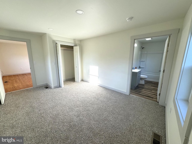 unfurnished bedroom featuring connected bathroom, carpet flooring, and a closet