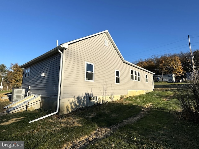 view of side of home featuring central AC unit and a yard