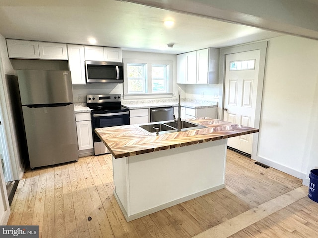 kitchen with white cabinetry, light wood-type flooring, appliances with stainless steel finishes, and a center island with sink