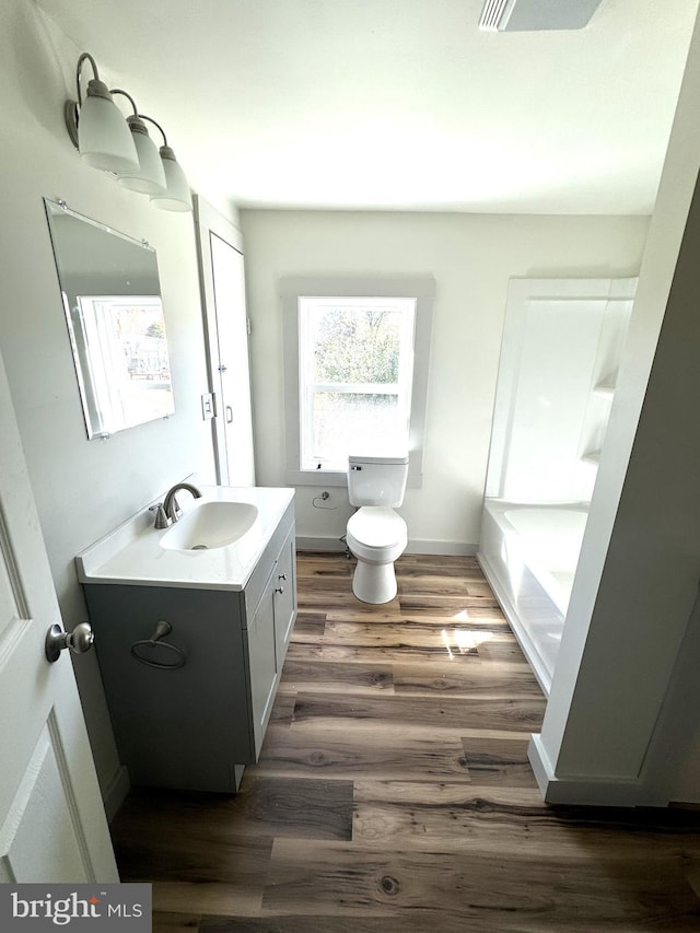 bathroom featuring toilet, a tub to relax in, vanity, and hardwood / wood-style floors