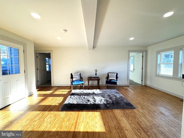 sitting room featuring beam ceiling, wood-type flooring, and plenty of natural light