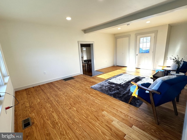 living room featuring light wood-type flooring and beam ceiling