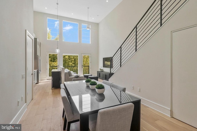 dining area featuring plenty of natural light, light hardwood / wood-style floors, and a high ceiling