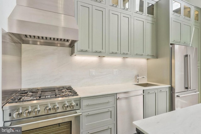 kitchen featuring light stone countertops, backsplash, wall chimney exhaust hood, sink, and high quality appliances