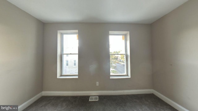 empty room featuring dark carpet and a healthy amount of sunlight