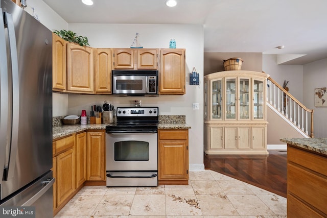 kitchen with appliances with stainless steel finishes, light tile patterned floors, and light stone counters