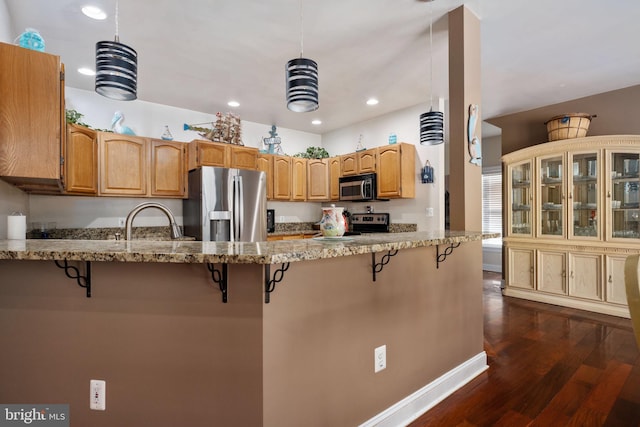 kitchen featuring dark wood-type flooring, a breakfast bar area, stainless steel appliances, and kitchen peninsula