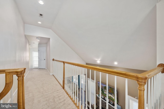 corridor with lofted ceiling and light colored carpet