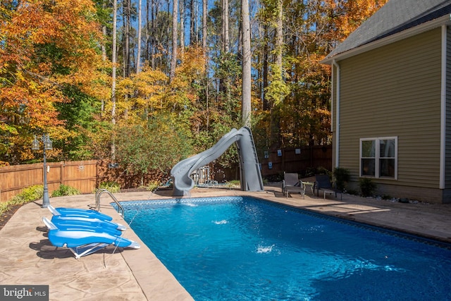 view of swimming pool with a water slide and a patio area