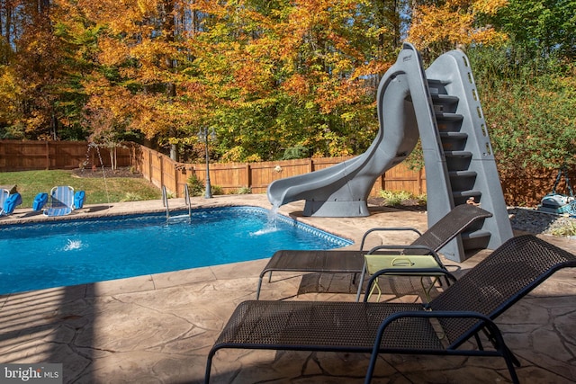 view of pool featuring pool water feature, a water slide, and a patio area