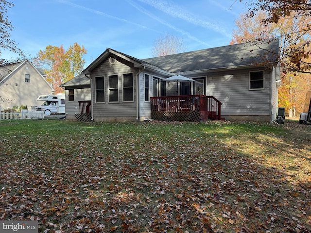 back of house with a deck and a lawn