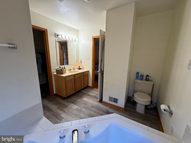 bathroom with vanity, a tub, hardwood / wood-style flooring, and toilet