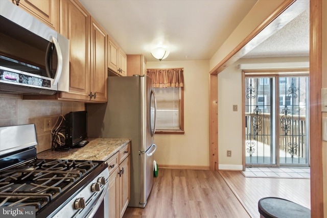 kitchen featuring stainless steel appliances, light stone countertops, light hardwood / wood-style flooring, and light brown cabinets