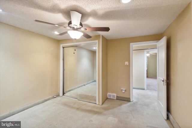 unfurnished bedroom with light carpet, a closet, a textured ceiling, and ceiling fan