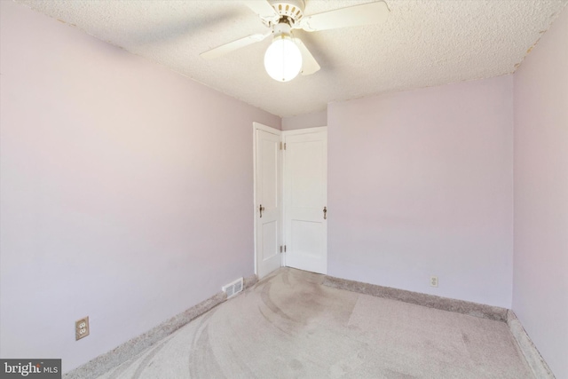 carpeted spare room with a textured ceiling and ceiling fan