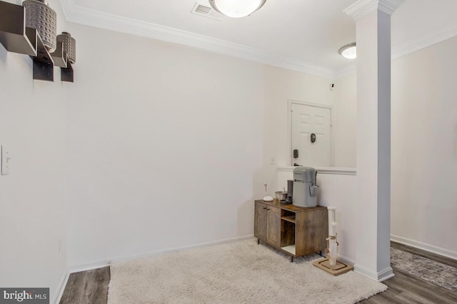 interior space featuring decorative columns, crown molding, and wood-type flooring