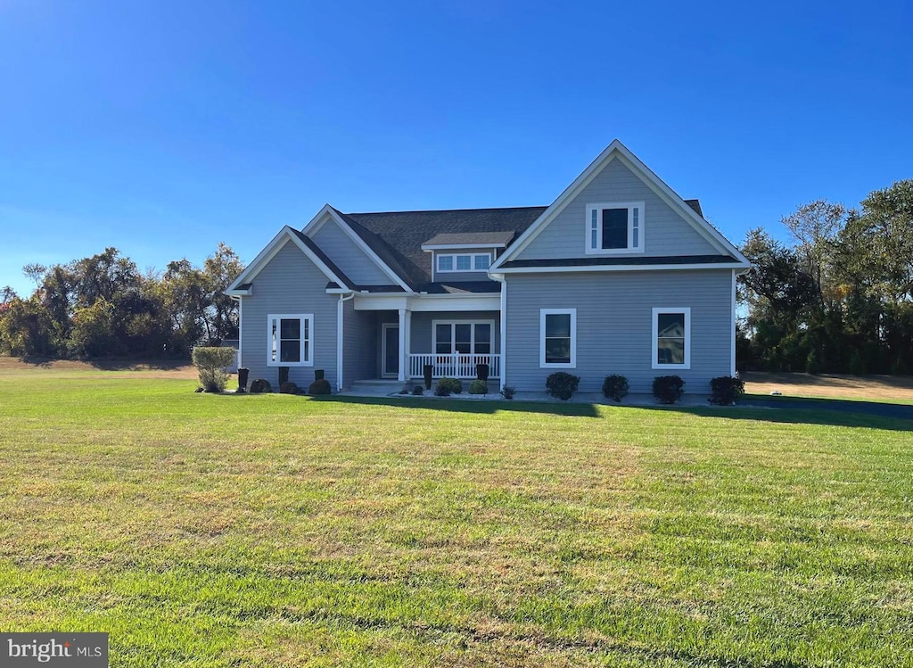 rear view of house featuring covered porch and a yard