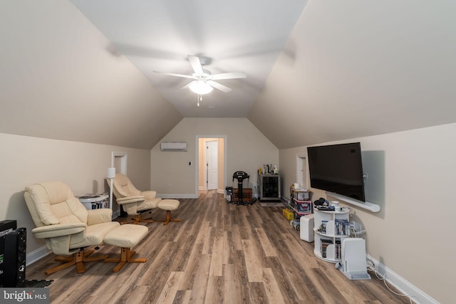 sitting room with a wall unit AC, lofted ceiling, hardwood / wood-style flooring, and ceiling fan