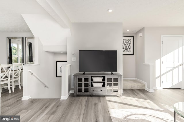 living room with a textured ceiling and light hardwood / wood-style flooring