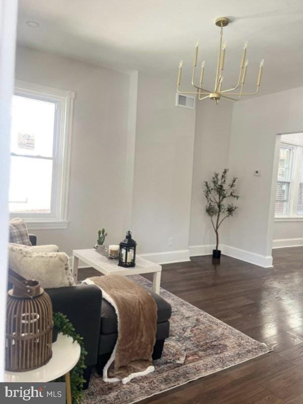 living room featuring an inviting chandelier and dark hardwood / wood-style floors