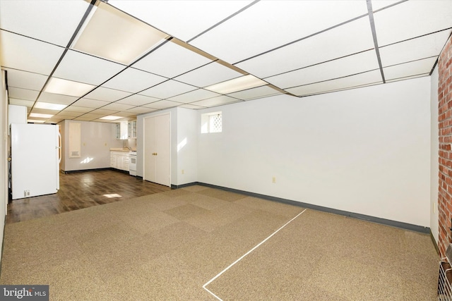 basement with dark hardwood / wood-style flooring, white refrigerator, and a drop ceiling