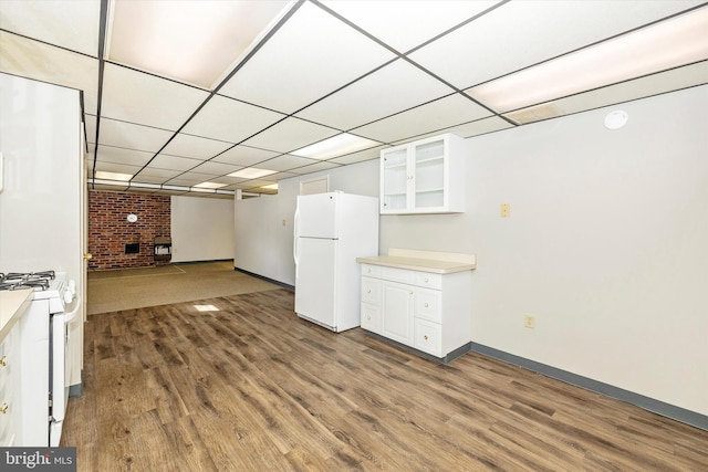 basement with a paneled ceiling, white refrigerator, a fireplace, and hardwood / wood-style floors