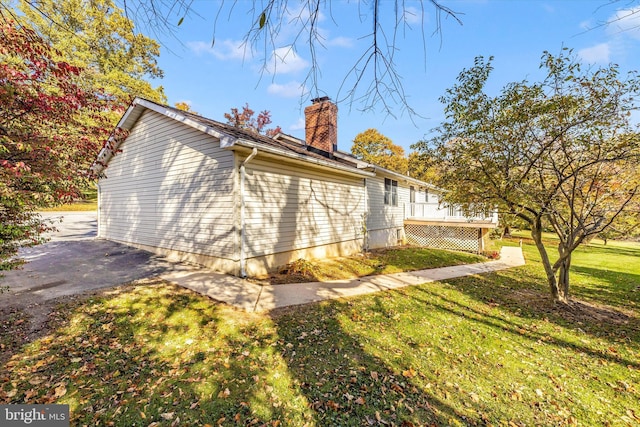 view of side of home with a wooden deck and a lawn