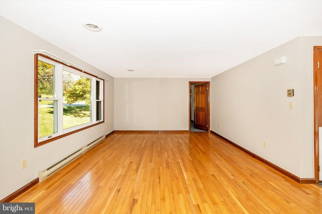 unfurnished room featuring a baseboard heating unit and light wood-type flooring