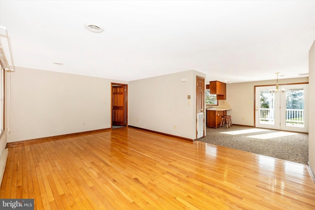 unfurnished living room featuring a chandelier and light wood-type flooring