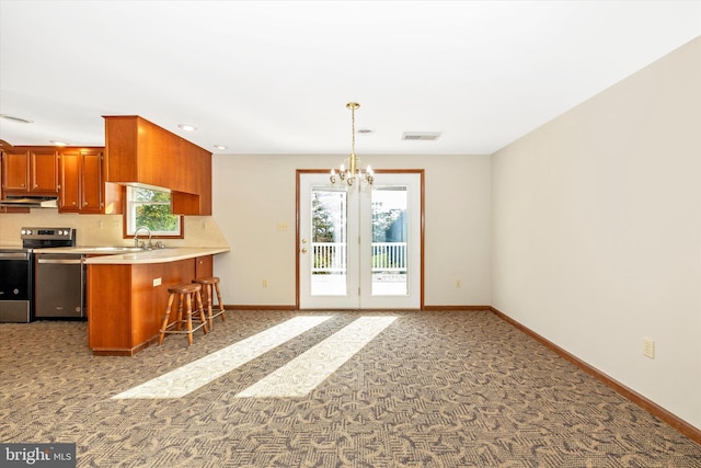 kitchen featuring kitchen peninsula, stainless steel appliances, backsplash, sink, and pendant lighting