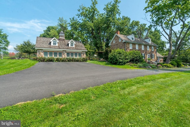 view of front of house with fence, aphalt driveway, and a front yard