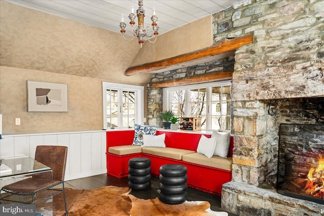 living room featuring lofted ceiling, a wainscoted wall, dark wood finished floors, and a notable chandelier