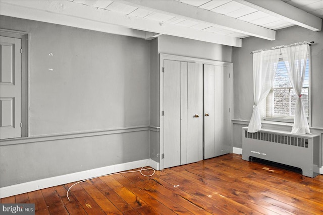 unfurnished bedroom featuring dark wood-style flooring, radiator, beamed ceiling, and baseboards