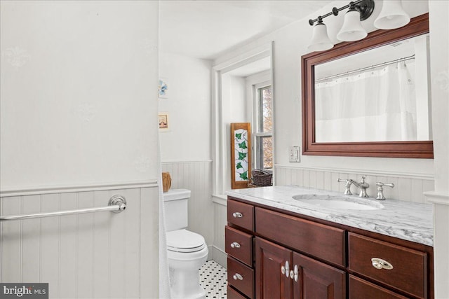 full bathroom featuring a wainscoted wall, toilet, and vanity