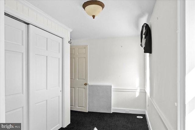 interior space featuring dark carpet and wainscoting