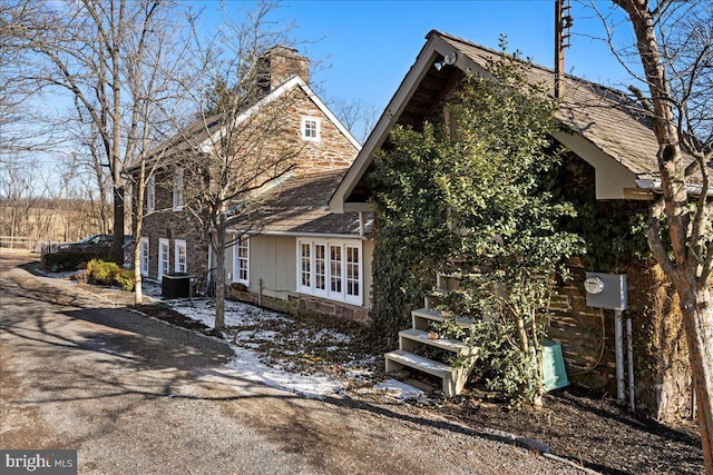 view of side of home featuring a chimney and central air condition unit