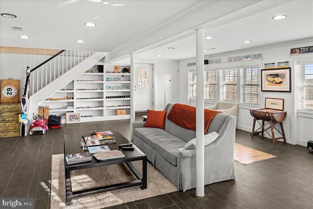 living area with ornamental molding, visible vents, dark wood finished floors, and stairs