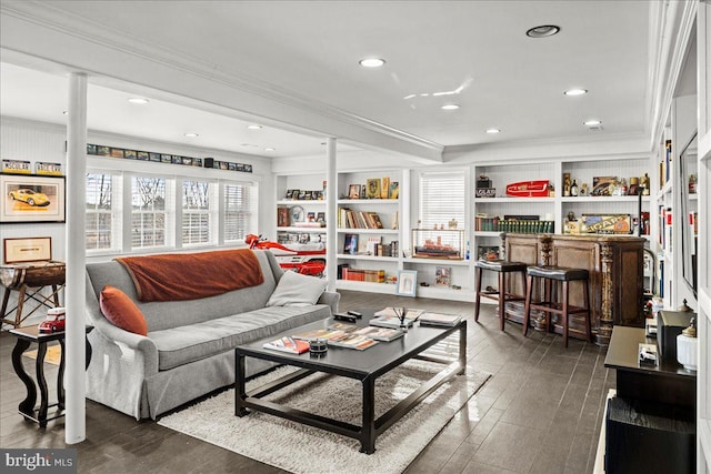 living room featuring built in shelves, dark wood-style flooring, crown molding, and recessed lighting