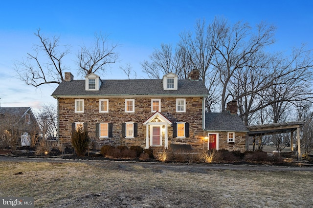 view of front of property with stone siding, a chimney, and a front yard