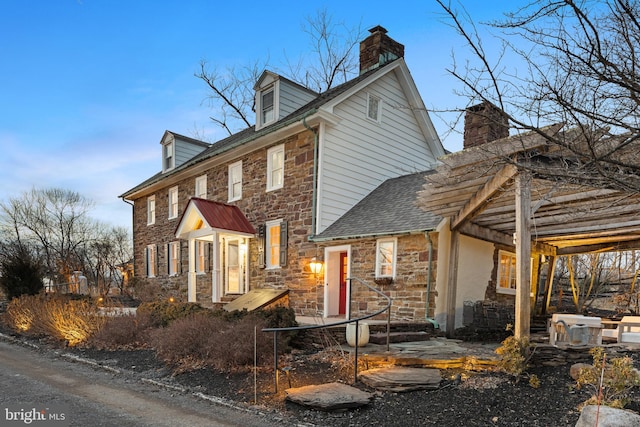 view of front of home featuring stone siding and a chimney