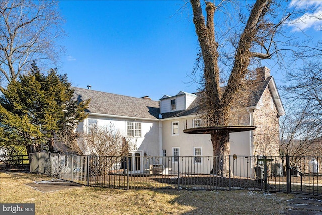 back of property featuring a yard, a fenced front yard, a chimney, and stucco siding