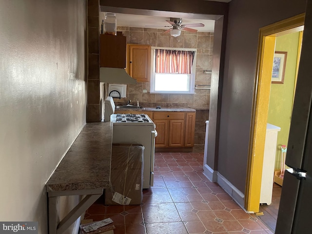 kitchen featuring white gas stove, sink, ventilation hood, and ceiling fan