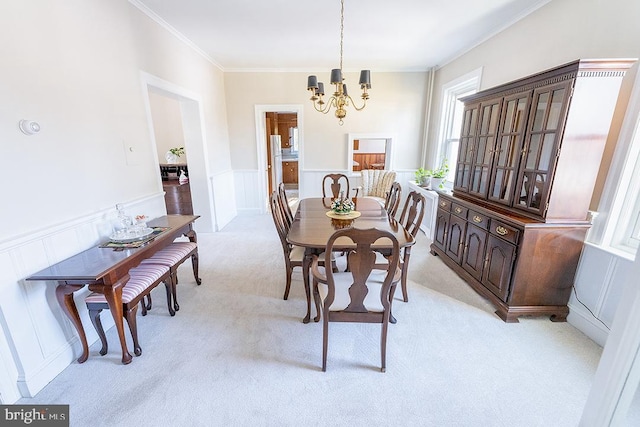 dining room featuring a notable chandelier, ornamental molding, and light carpet