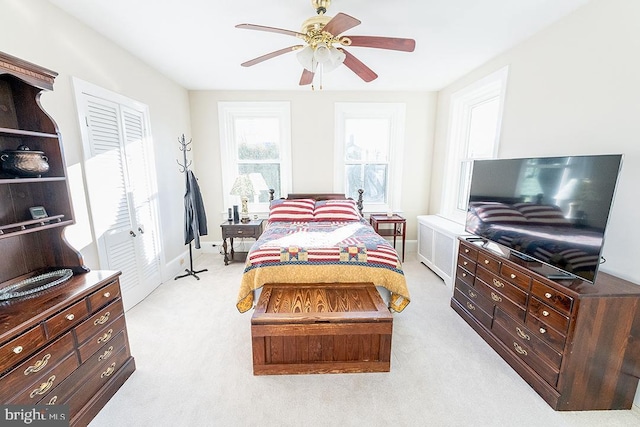 bedroom with ceiling fan, light colored carpet, and a closet