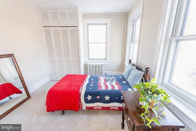 carpeted bedroom with radiator heating unit, a closet, and multiple windows