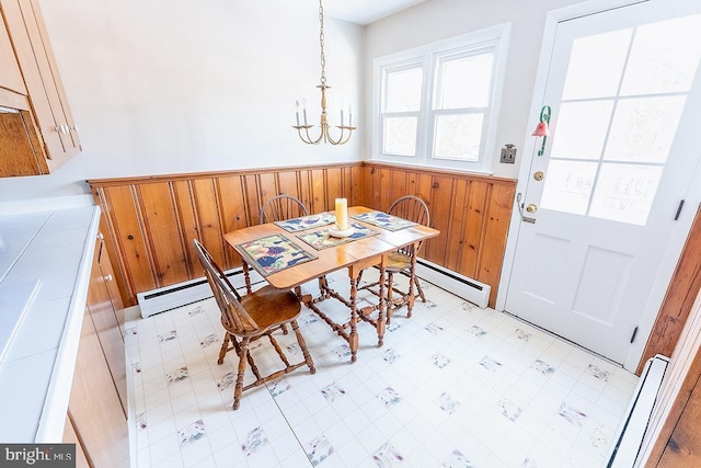 dining room featuring a chandelier, wooden walls, and a baseboard heating unit