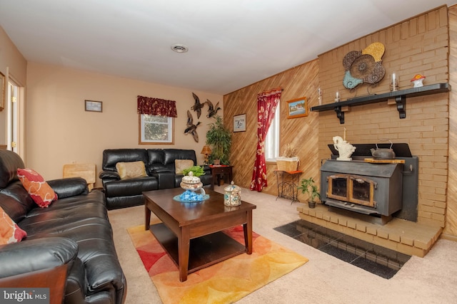 living room featuring a wood stove, light carpet, and wooden walls